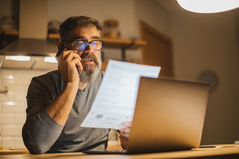 mężczyzna rozmawia przez telefon przeglądając dokumenty